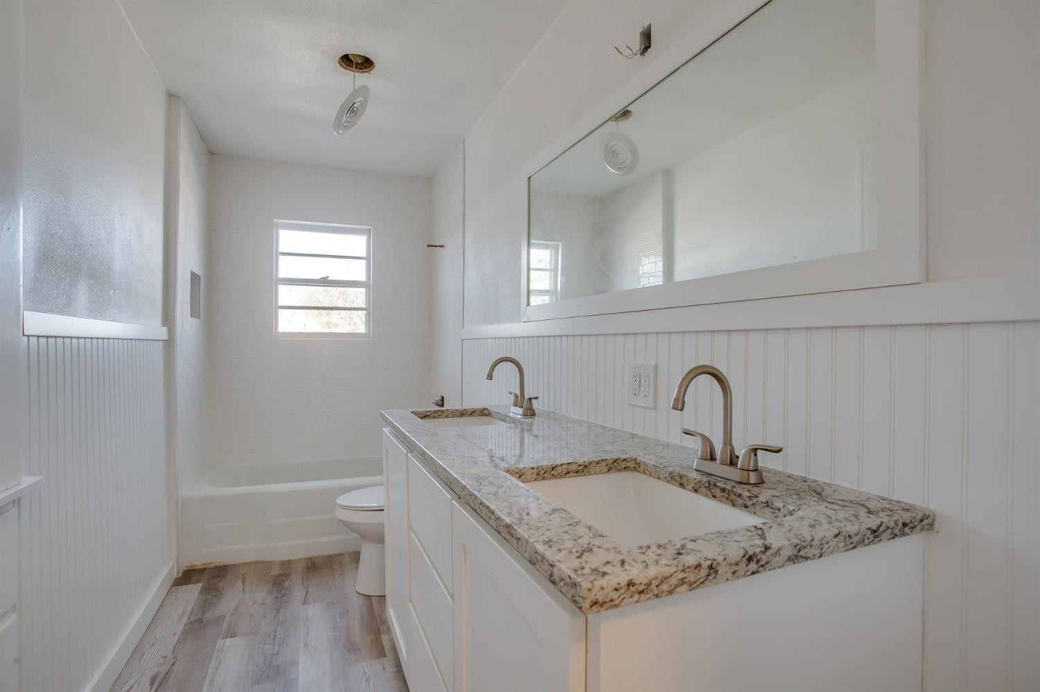 5002 41st Street Lubbock, TX 79414 - Photo 11 of 13 a bathroom with a granite countertop sink a toilet and a bathtub