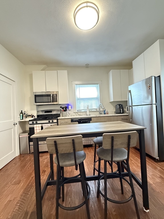 229 Charles Street, Unit 1 Cambridge, MA 02141 - Photo 18 of 19 a kitchen with stainless steel appliances granite countertop a stove a refrigerator a microwave a dining table and chairs