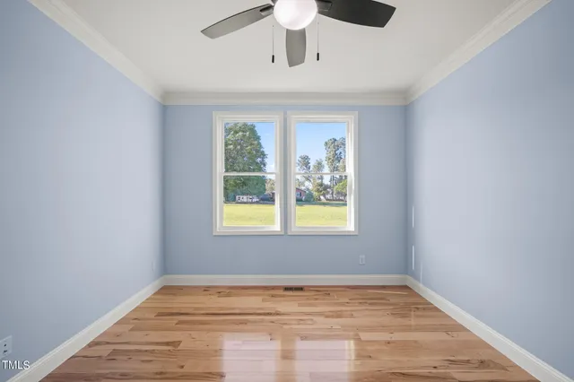 a view of empty room with wooden floor and fan