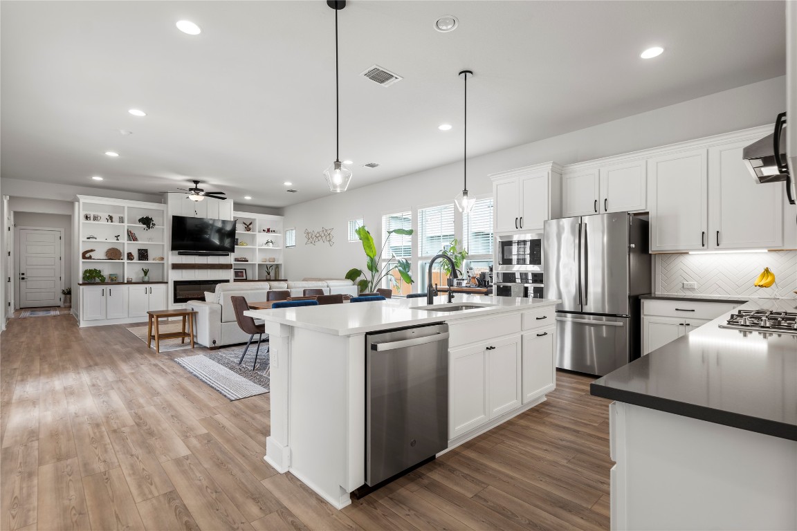 a kitchen with stainless steel appliances white cabinets a sink a stove a refrigerator and a oven