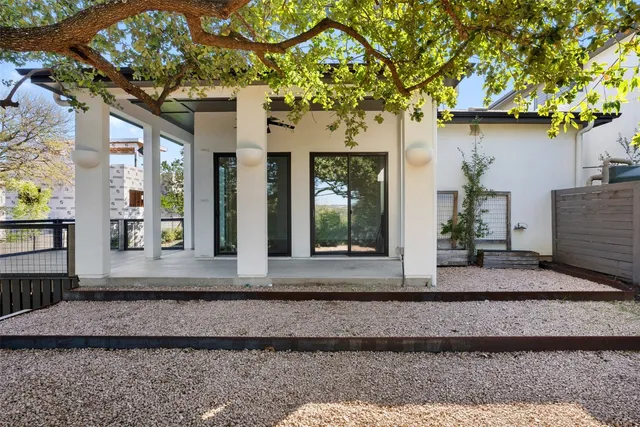 a view of a house with potted plants and large tree