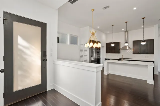 a kitchen with stainless steel appliances granite countertop a refrigerator a oven and white cabinets with wooden floor