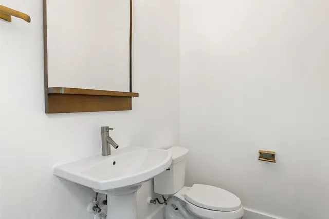 a bathroom with a toilet a sink and mirror