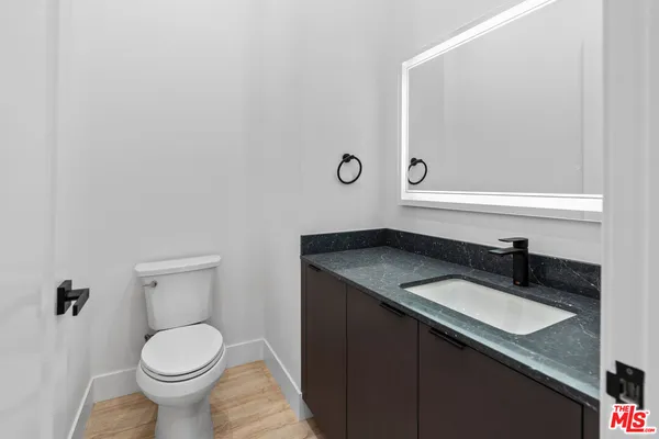 a bathroom with a granite countertop toilet sink and mirror