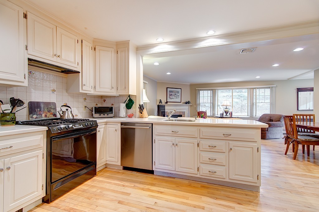 61 Silver Hill Road Weston, MA 02493 - Photo 6 of 18 a kitchen with granite countertop a stove a sink a dining table and chairs with wooden floor