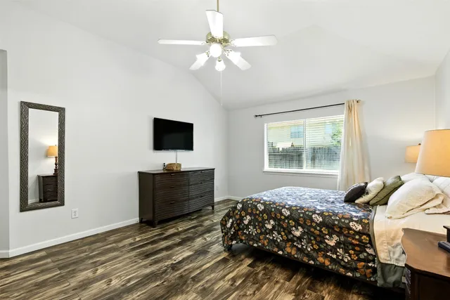 a bedroom with a bed potted plant on dresser and a window