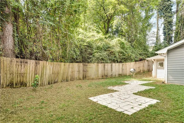 a view of a brick house next to a yard with large trees