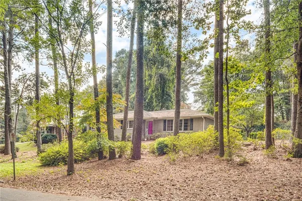 a view of a brick house next to a yard with large trees