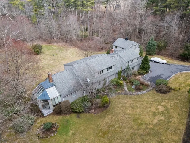 an aerial view of a house with a yard and large tree