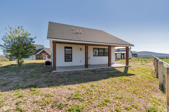 1820 West Farmhouse Flats Road Peoa, UT 84061 - Photo 74 of 79 White vertical plank siding building featuring a dark shingle roof and a covered concrete patio
