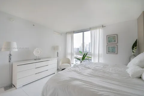 a bedroom with a bed and large windows