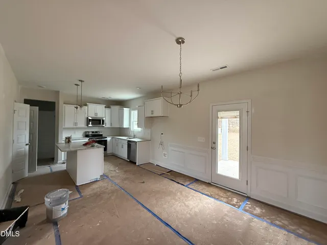 a kitchen with a sink dishwasher a stove and white cabinets with wooden floor