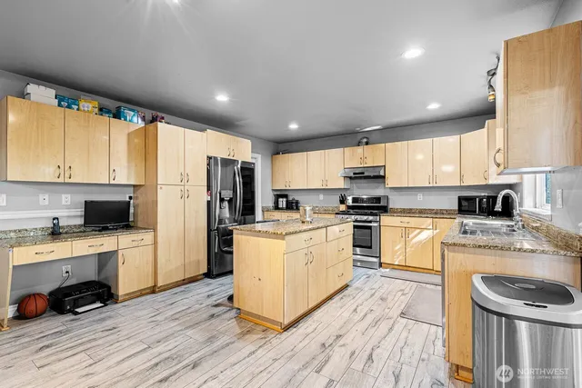 a kitchen with a refrigerator a stove top oven a sink a cabinets and wooden floor