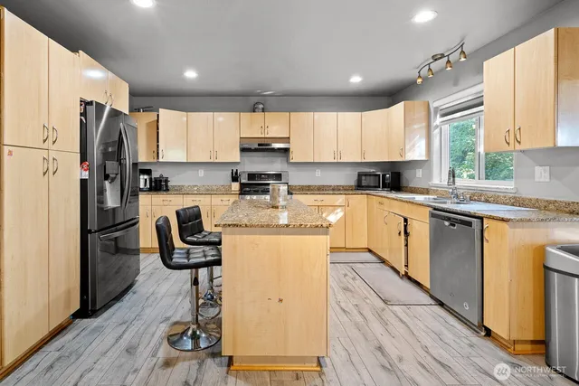 a kitchen with a refrigerator a sink dishwasher a stove and white cabinets with wooden floor