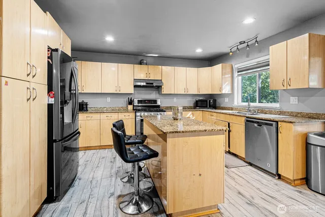 a kitchen with a refrigerator a sink dishwasher a stove and white cabinets with wooden floor