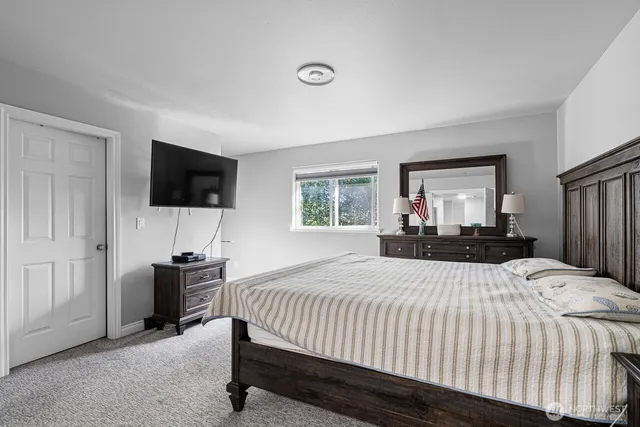 a bed room with a bed a television and a large window