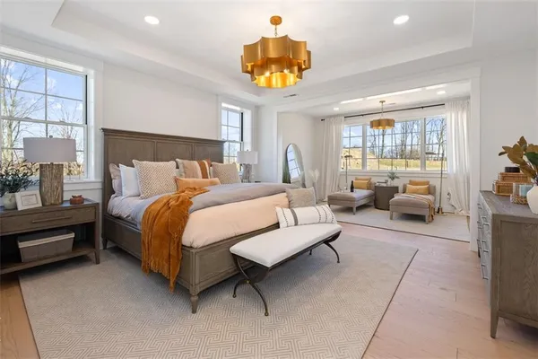 a bedroom with a bed couch chandelier and window