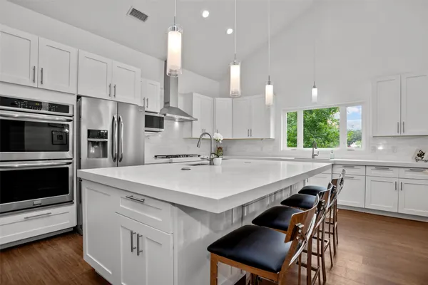 a kitchen with stainless steel appliances a sink a stove a refrigerator cabinets and a window
