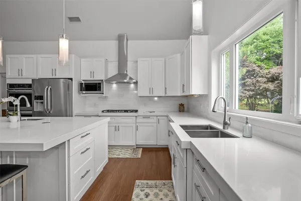 a kitchen with a sink a stove a refrigerator and white cabinets