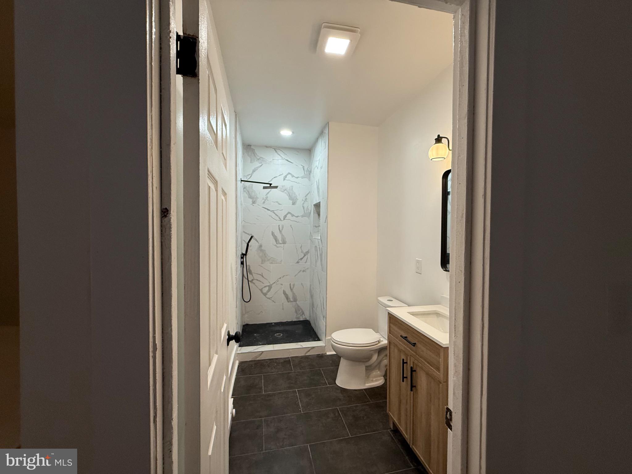 114 South 58th Street, Unit 1 Philadelphia, PA 19139 - Photo 10 of 15 a bathroom with a granite countertop toilet and a shower