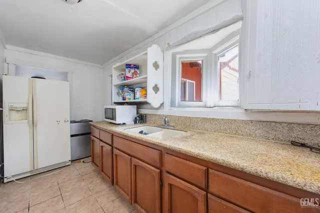 a utility room with stainless steel appliances granite countertop a sink dishwasher and a microwave oven