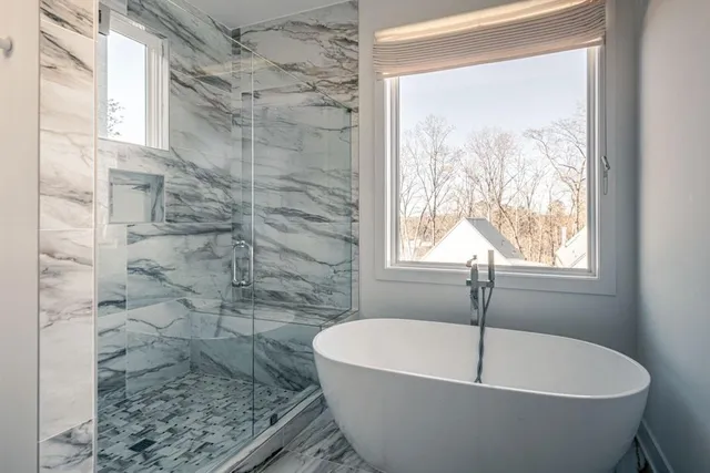 a white bath tub sitting in a bathroom next to a window
