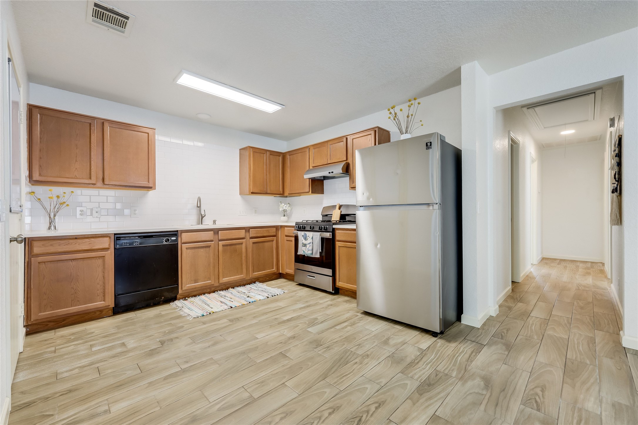 4510 Secure Lane Austin, TX 78725 - Photo 8 of 24 a kitchen with a refrigerator a stove top oven a sink and dishwasher with wooden floor