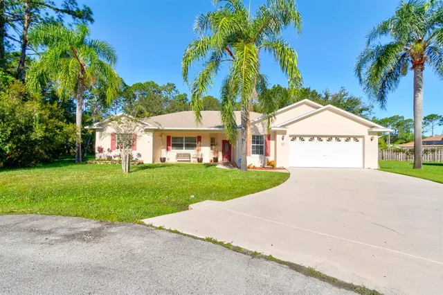 a view of a white house with a small yard and palm trees
