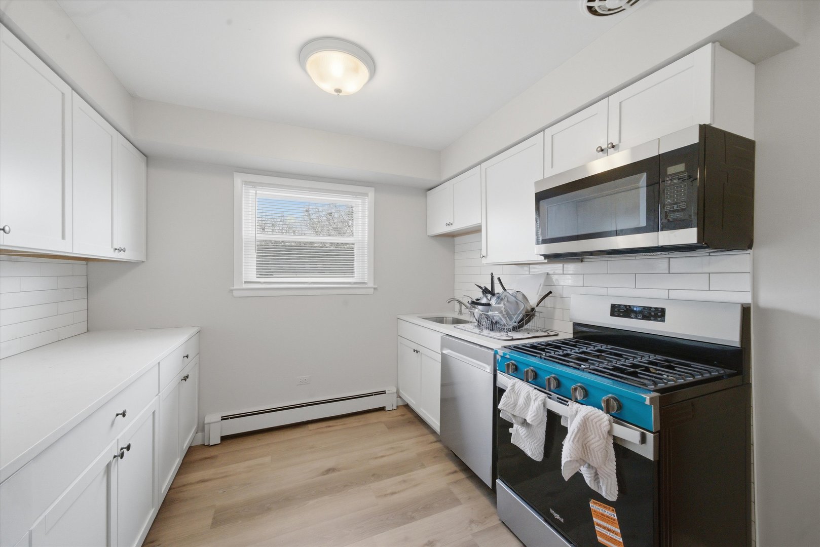 7412 West 63rd Place Summit, IL 60501 - Photo 25 of 49 a kitchen with stainless steel appliances a stove a microwave a sink and cabinets