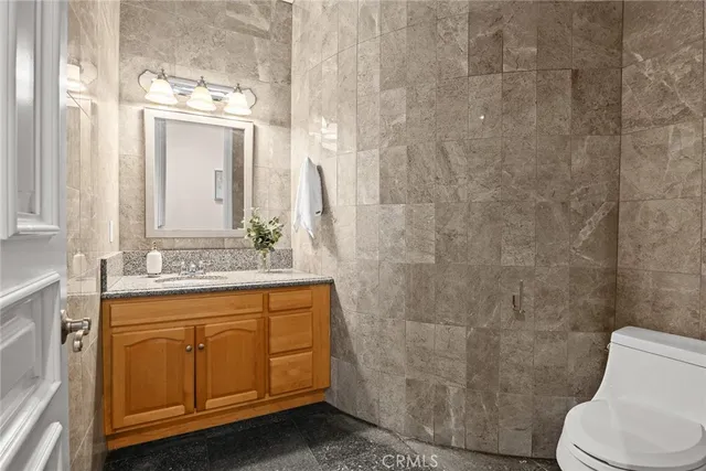 a bathroom with a granite countertop toilet sink and mirror