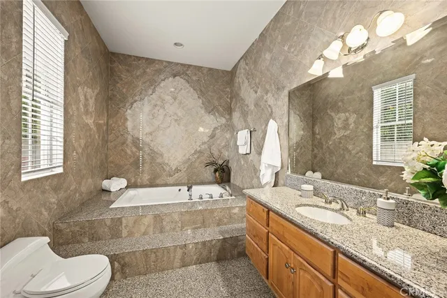 a bathroom with a granite countertop double vanity sink a toilet and a bathtub