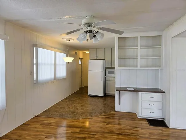 a view of a kitchen with a fridge and wooden floor