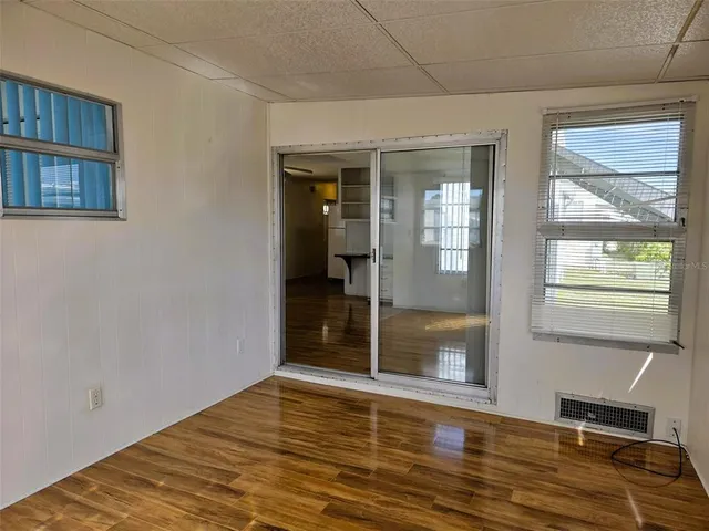 a view of an empty room with wooden floor and a window