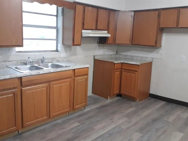 a kitchen with stainless steel appliances granite countertop wooden cabinets a sink and dishwasher with wooden floor