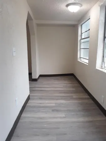 a view of an empty room with wooden floor and a window