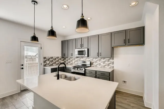 a kitchen with stainless steel appliances kitchen island granite countertop a sink a stove and refrigerator