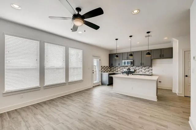 a kitchen with stainless steel appliances kitchen island hardwood floor sink stove and wooden cabinets