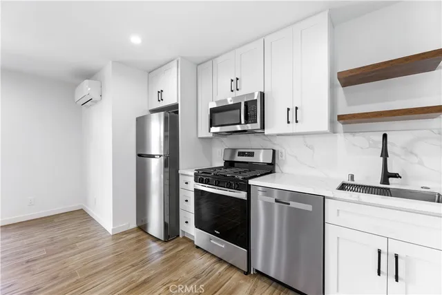 a kitchen with stainless steel appliances a sink cabinets and a wooden floor