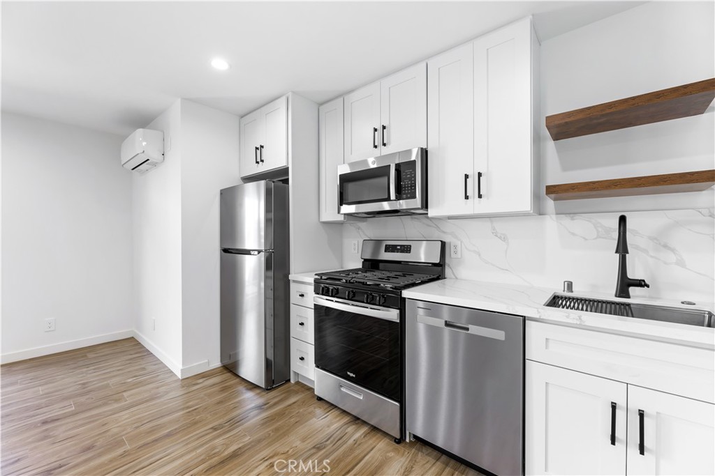 a kitchen with stainless steel appliances a sink cabinets and a wooden floor