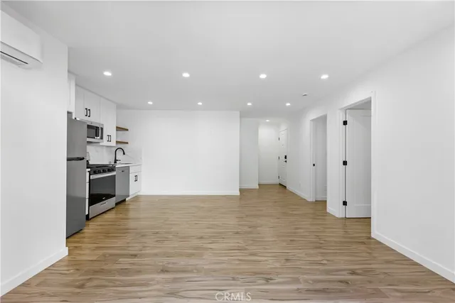 a view of kitchen with kitchen island wooden floor center island and stainless steel appliances