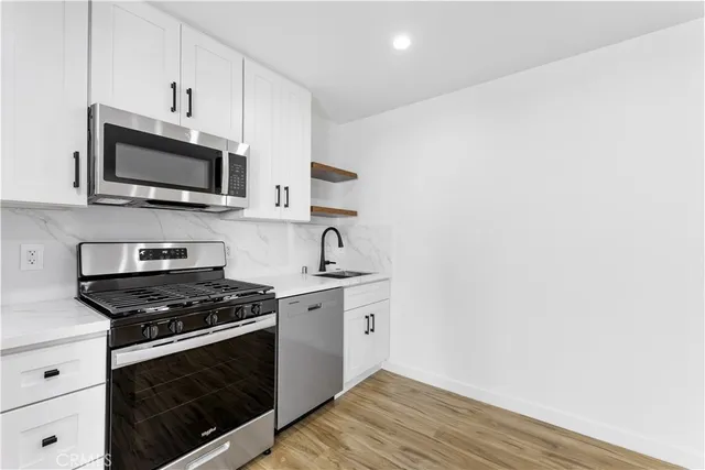 a kitchen with stainless steel appliances a stove microwave and sink