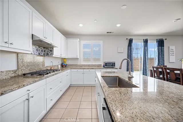 a large kitchen with granite countertop a large counter top stainless steel appliances and cabinets