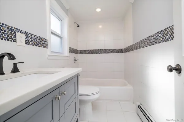 a bathroom with a granite countertop sink a toilet and bathtub