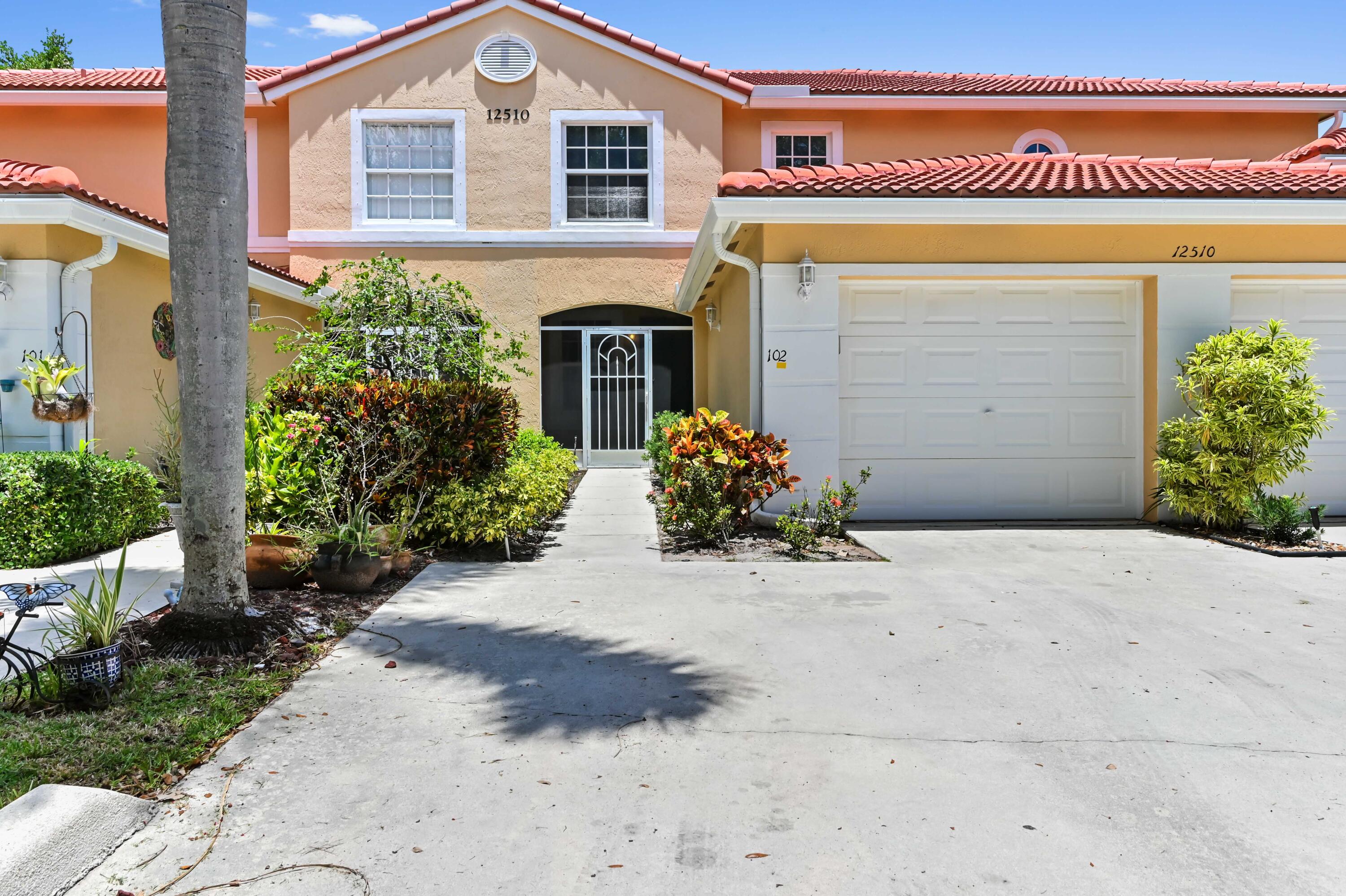 12510 Crystal Pointe Drive, Unit 102 Boynton Beach, FL 33437 - Photo 2 of 27 a front view of a house with a yard and a garage