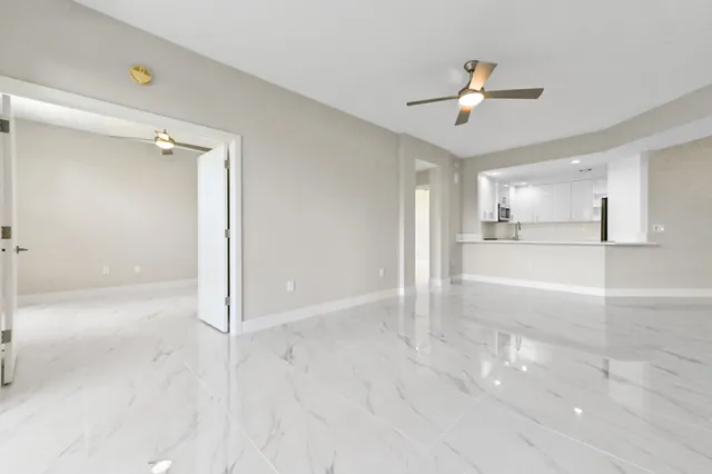 a view of a livingroom with a chandelier fan and kitchen view