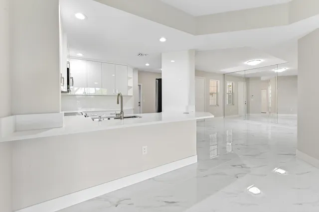 a view of kitchen with kitchen island a sink stainless steel appliances and white cabinets