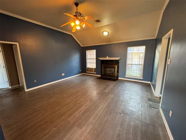 an empty room with wooden floor a fireplace and windows