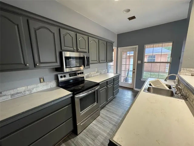 a kitchen with granite countertop wooden cabinets a stove and a sink