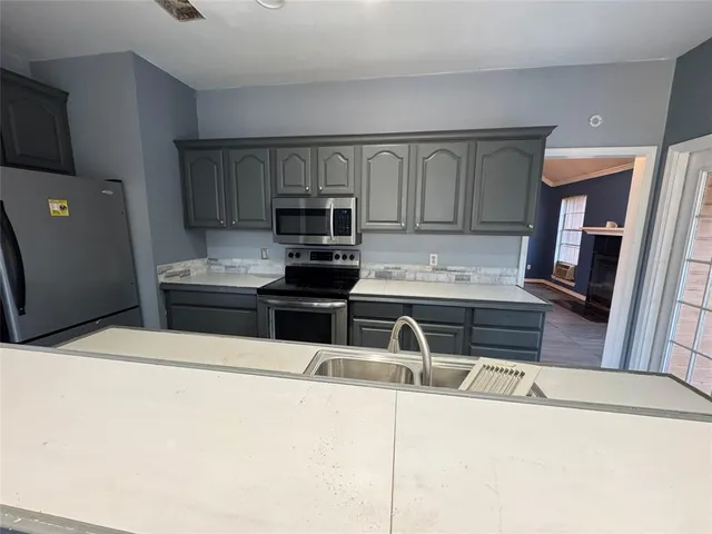 a kitchen with stainless steel appliances a stove a microwave a sink and cabinets