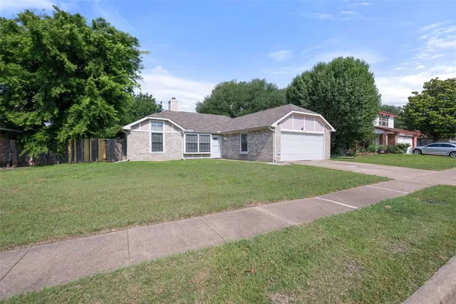 a view of yellow house with a big yard and large trees